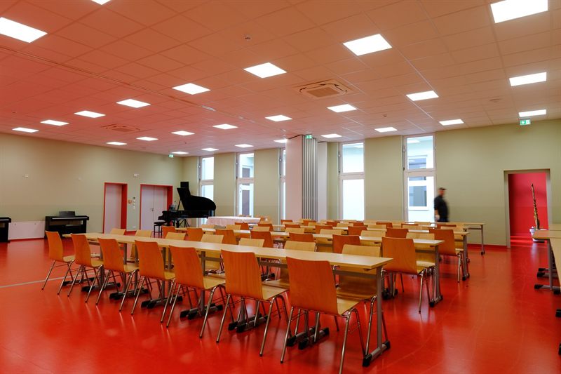Assembly hall with rows of tables, grand piano and piano