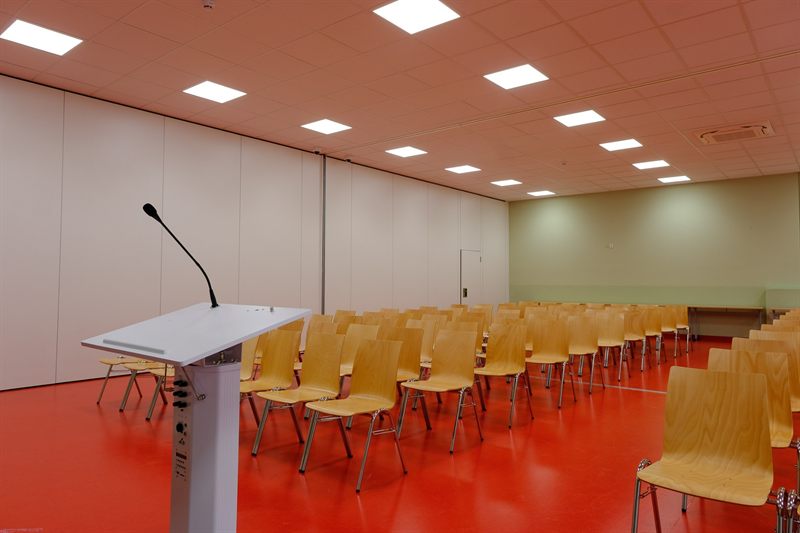 Assembly hall with lectern and rows of chairs, mobile partition closed